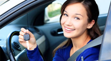 Female driver in a white car showing the car key